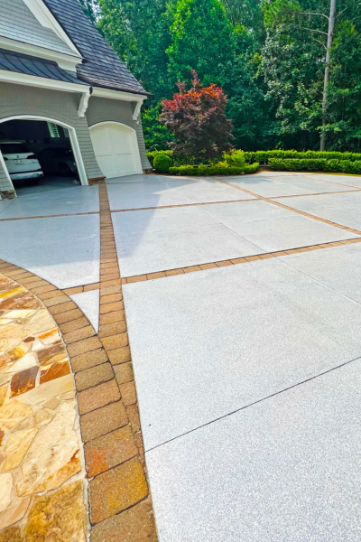 Light grey polyaspartic coated driveway with brick trim.