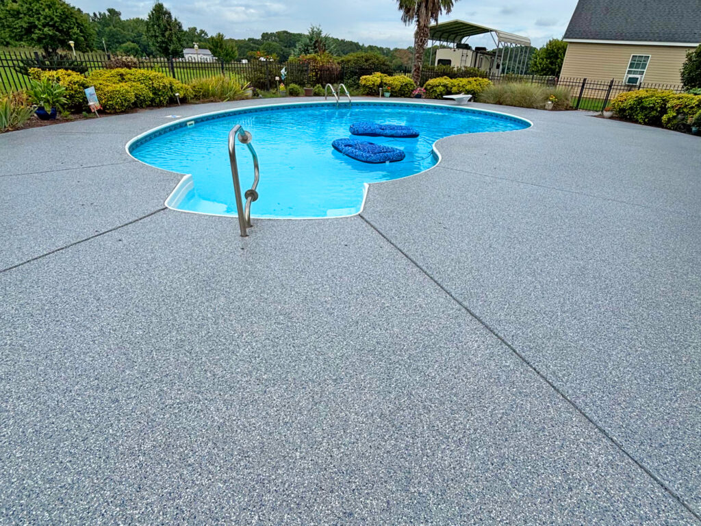 Stonewash textured pool deck coating surrounding a backyard swimming pool.